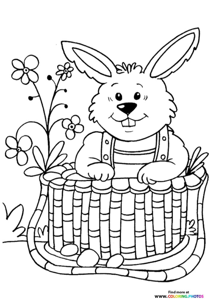 Smiling Easter bunny in striped overalls sitting in a woven basket with spring flowers coloring page